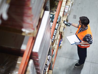 Worker with scanner making review of goods in warehouse